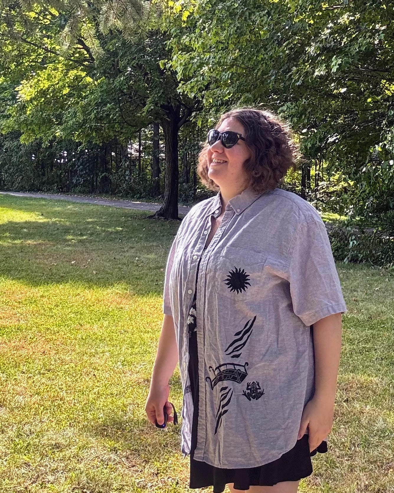 Over the Bridge; grey short sleeve top featuring a bicycle, bridge, and fairy cottage