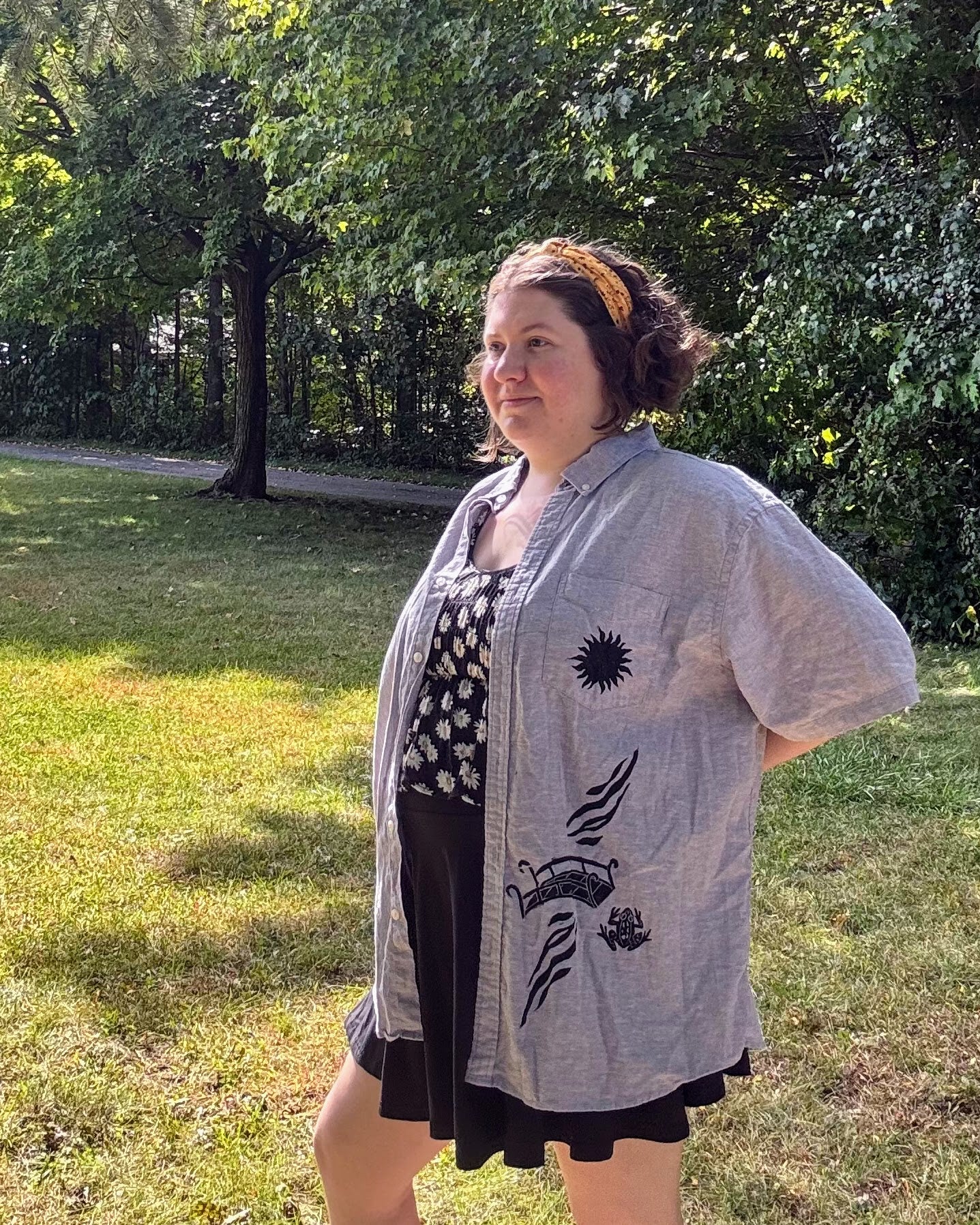 Over the Bridge; grey short sleeve top featuring a bicycle, bridge, and fairy cottage