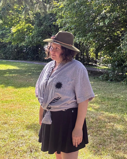 Over the Bridge; grey short sleeve top featuring a bicycle, bridge, and fairy cottage